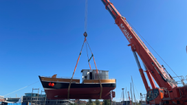 Ein Holzschiff an einem Kran über dem WasserÖffnet Seite: Kutter "Marlen" wieder mit dem Ostseewasser in Berührung