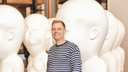 Stefan Stahl steht neben weißen mannshohen Kunststatuen, die an Babys erinnern.Öffnet Seite: Das richtige Leben